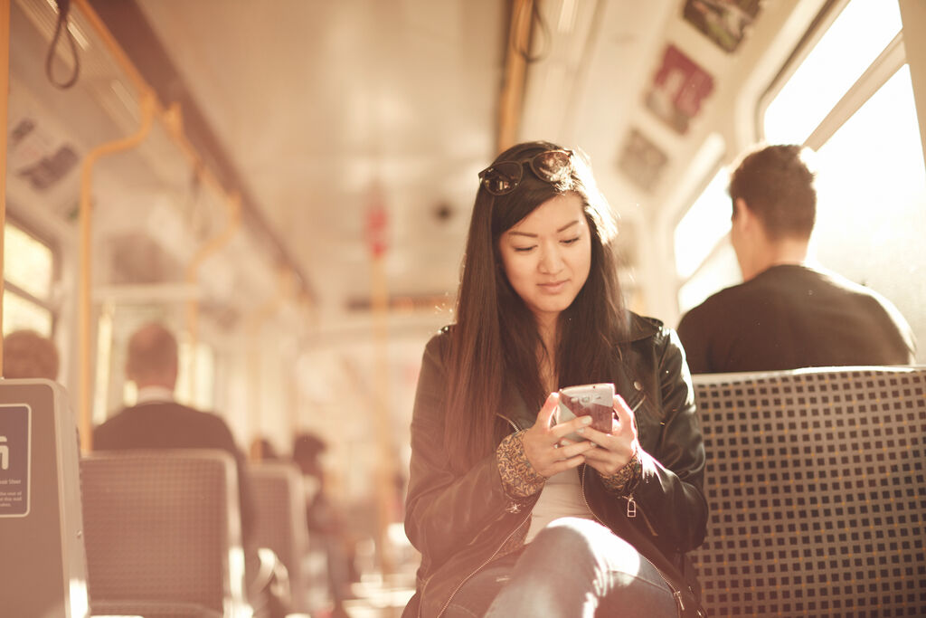 A female student looking at her phone on a Metro train