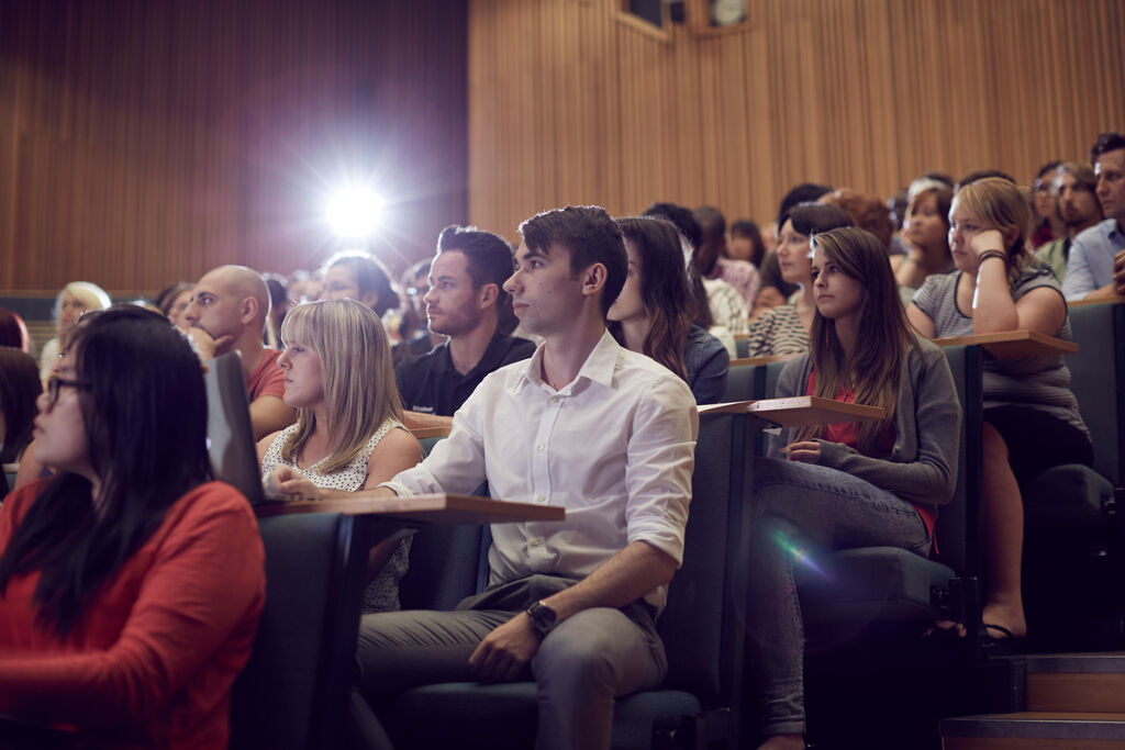 A busy lecture theatre with a bright light in the background.