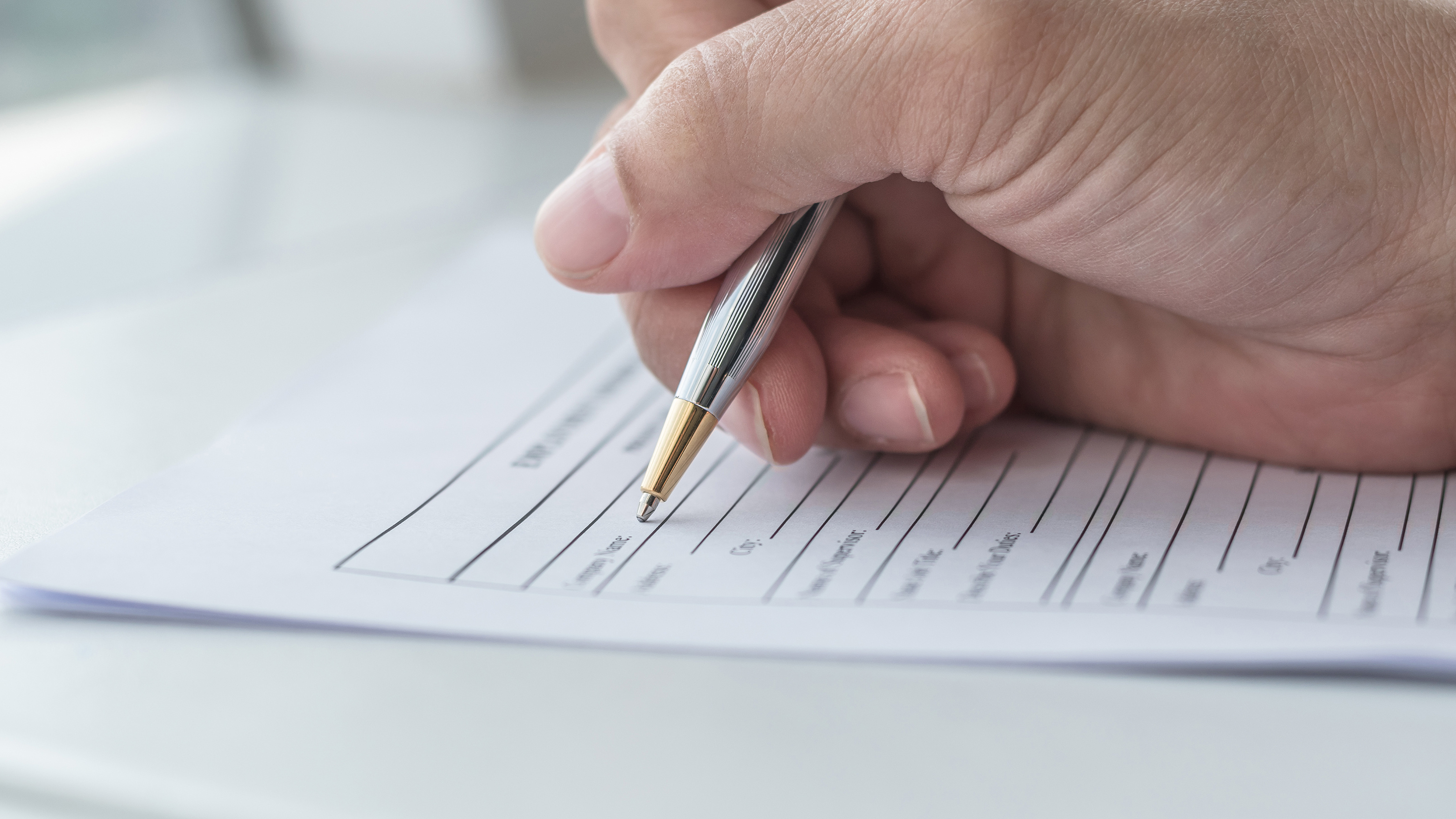 A hand using a pen to complete an application form